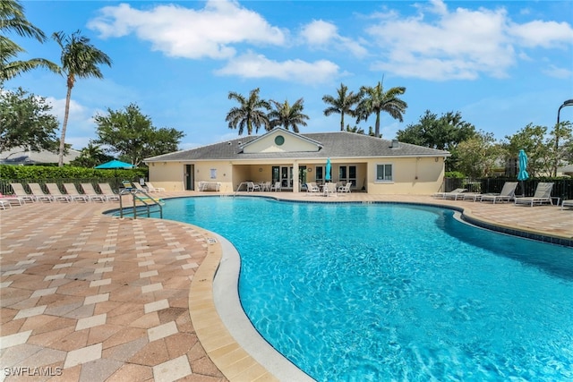 pool with a patio area and fence