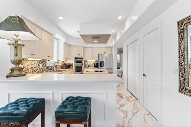 14356 Harbour Landings Dr Unit 6C, Fort Myers, FL 33908 - kitchen featuring appliances with stainless steel finishes, cream cabinetry, light countertops, tasteful backsplash, and a peninsula