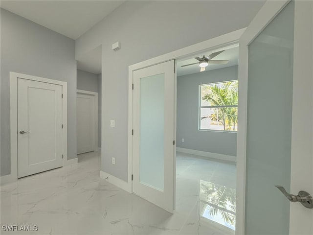 interior space with a ceiling fan, baseboards, and marble finish floor