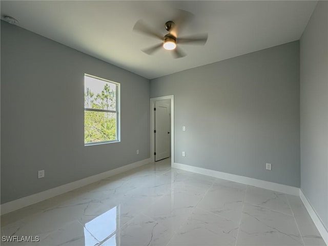 unfurnished room featuring baseboards, ceiling fan, and marble finish floor