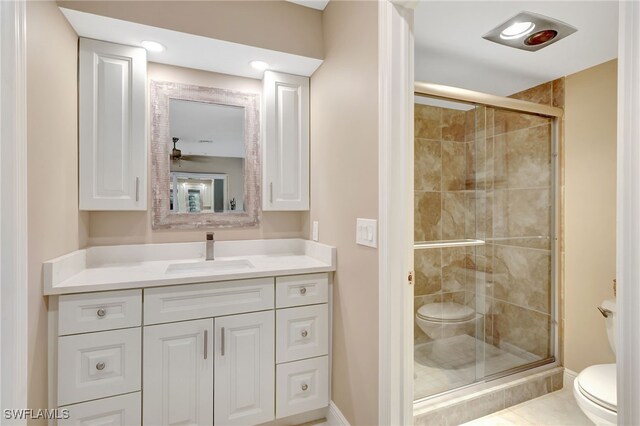 full bath featuring toilet, a stall shower, vanity, and baseboards