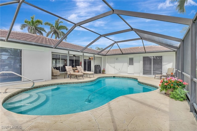 outdoor pool featuring glass enclosure, ceiling fan, and a patio area