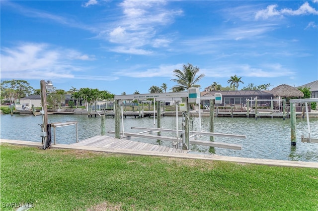 dock area featuring boat lift, a water view, and a yard