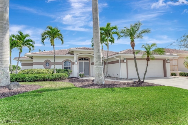 mediterranean / spanish home featuring stucco siding, a tiled roof, driveway, a front lawn, and an attached garage