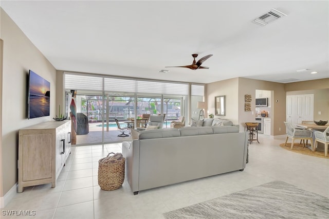 living room with a ceiling fan, baseboards, visible vents, and expansive windows