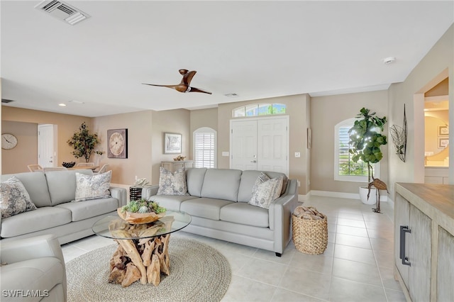 living area featuring light tile patterned floors, visible vents, a healthy amount of sunlight, and baseboards