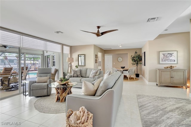 living room featuring light tile patterned flooring, visible vents, a ceiling fan, and baseboards