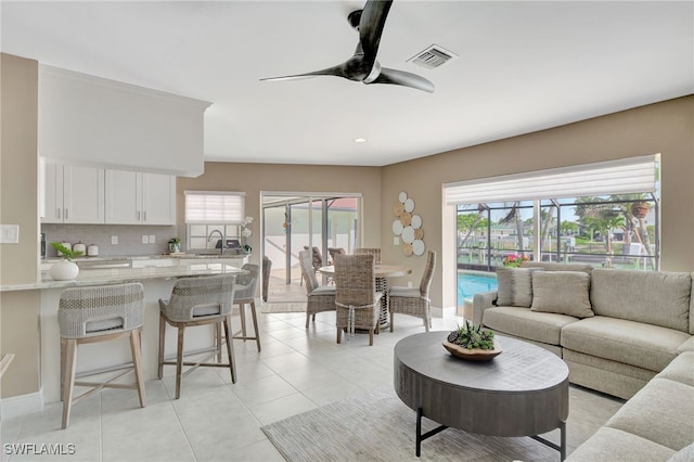 living room with light tile patterned floors, visible vents, ceiling fan, and a wealth of natural light