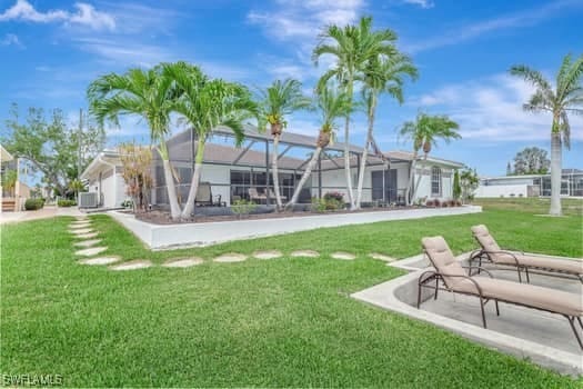 back of house with a lawn and a lanai