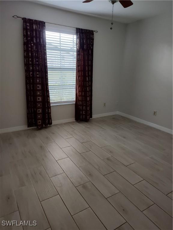 unfurnished room with light wood-style floors, a ceiling fan, and baseboards