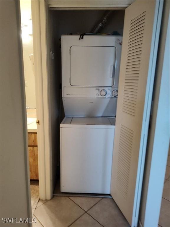 laundry room with light tile patterned flooring, stacked washing maching and dryer, and laundry area
