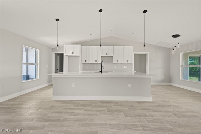 kitchen featuring a spacious island, light countertops, vaulted ceiling, white cabinets, and a sink