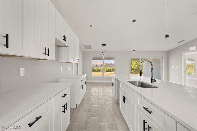 kitchen with a wealth of natural light, visible vents, white cabinets, and a sink