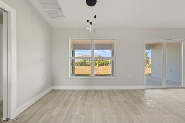 unfurnished room with light wood-style floors, visible vents, and baseboards