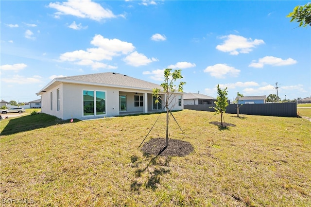 back of property featuring a lawn, stucco siding, and fence
