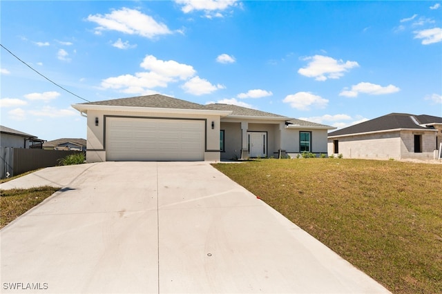 prairie-style home with stucco siding, fence, a garage, driveway, and a front yard