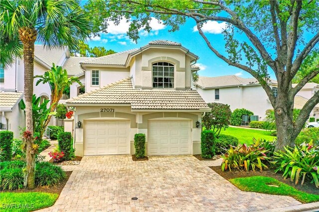 27071 Lake Harbor Ct Unit 103, Bonita Springs, FL 34134 - mediterranean / spanish house with stucco siding, decorative driveway, a garage, and a tiled roof