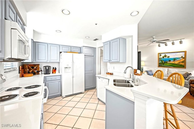 27071 Lake Harbor Ct Unit 103, Bonita Springs, FL 34134 - kitchen with white appliances, a sink, gray cabinets, a peninsula, and a breakfast bar