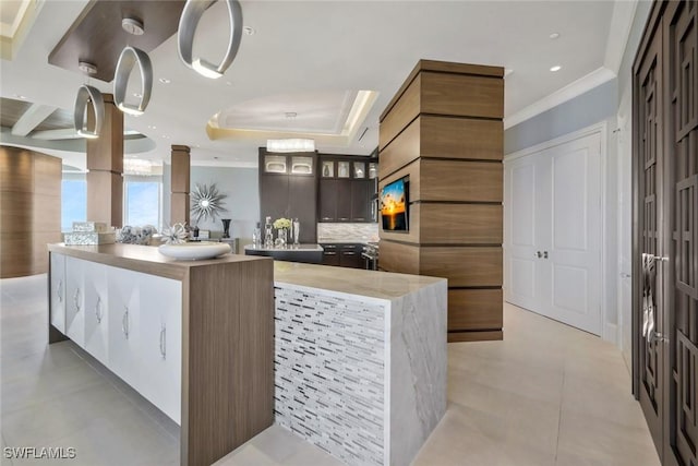 kitchen with crown molding, tasteful backsplash, glass insert cabinets, a kitchen island, and light tile patterned floors
