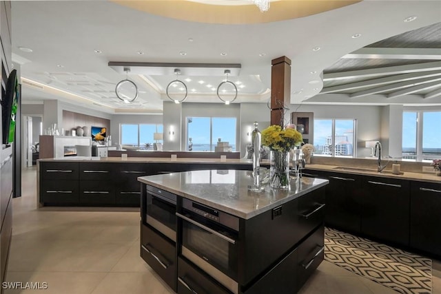kitchen with open floor plan, stainless steel microwave, a large island, a tray ceiling, and plenty of natural light