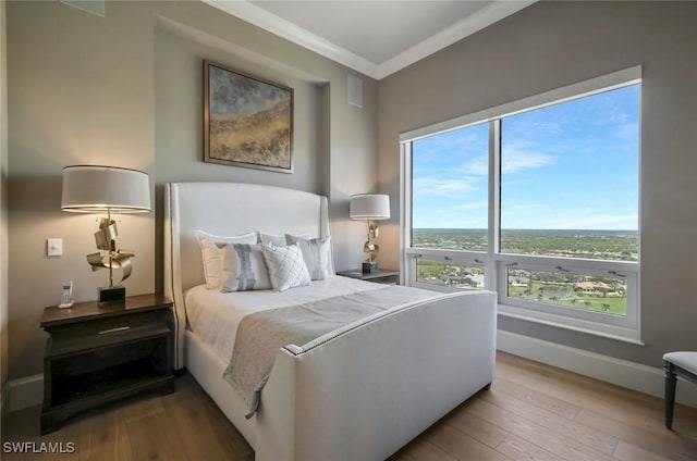 bedroom with crown molding, wood finished floors, and baseboards