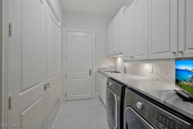 washroom featuring cabinet space, washing machine and dryer, and light tile patterned floors