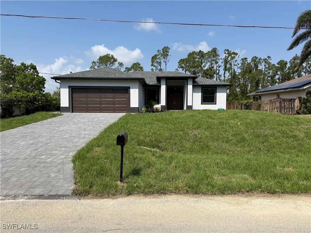 view of front of house with an attached garage, a front lawn, decorative driveway, and stucco siding
