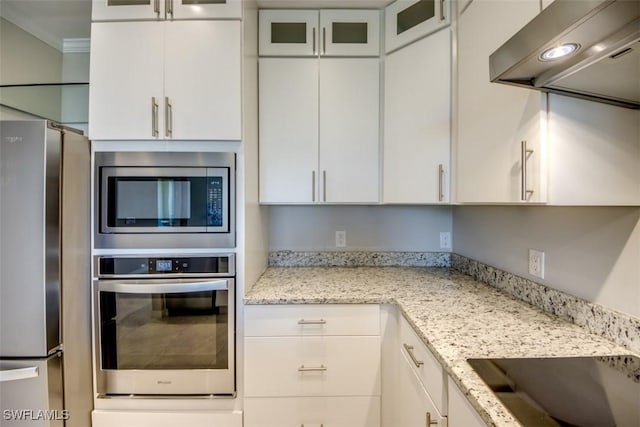 kitchen with under cabinet range hood, appliances with stainless steel finishes, white cabinetry, and glass insert cabinets