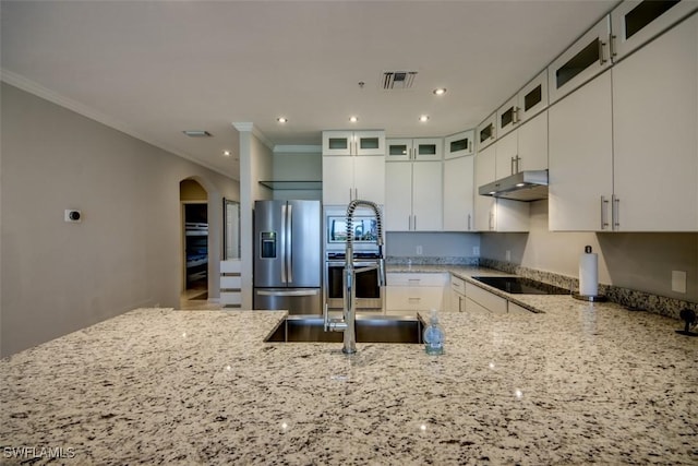 kitchen with crown molding, arched walkways, stainless steel appliances, light stone countertops, and visible vents