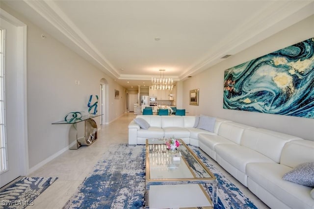 living room with a chandelier, a raised ceiling, baseboards, and light tile patterned floors