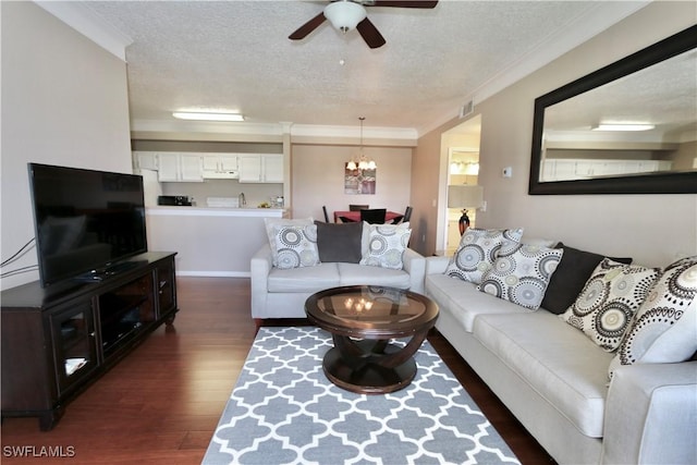 living area featuring crown molding, dark wood-style flooring, a textured ceiling, ceiling fan with notable chandelier, and visible vents