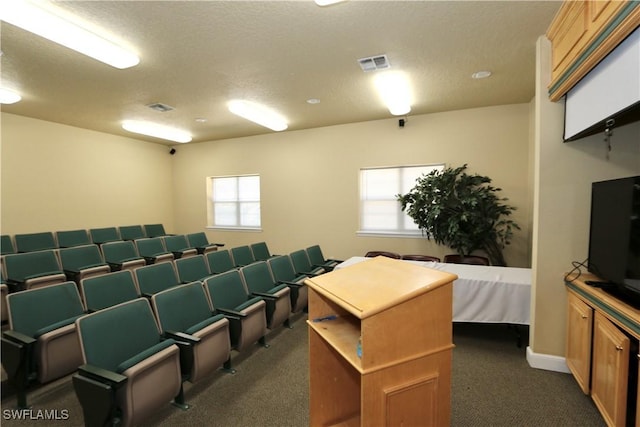 home theater room with visible vents, a textured ceiling, and dark carpet