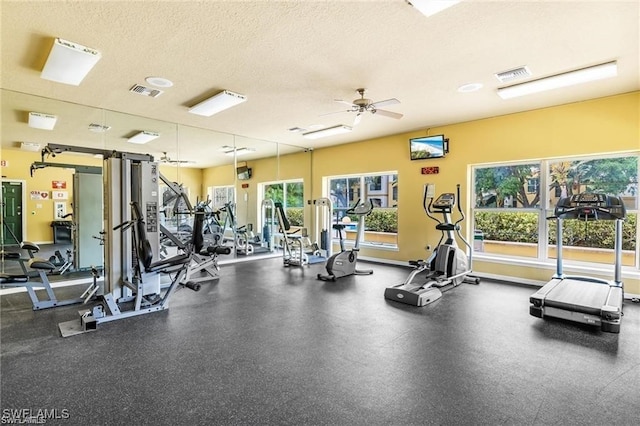 workout area featuring baseboards, a ceiling fan, a textured ceiling, and visible vents