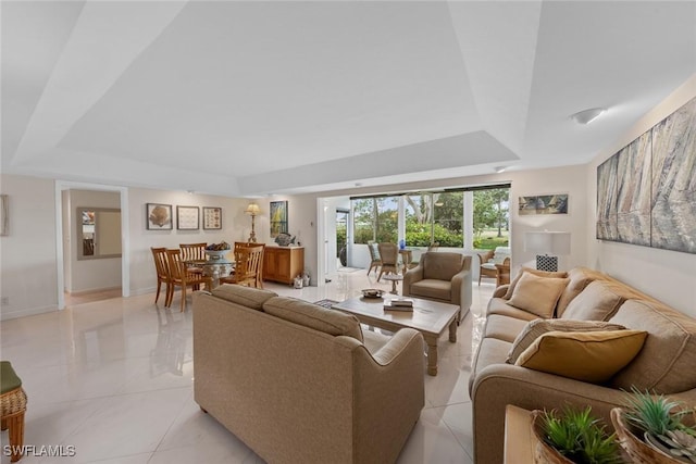 living room featuring baseboards and a tray ceiling