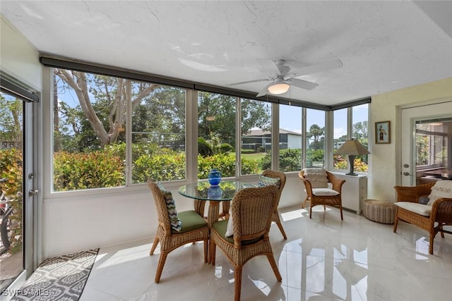 sunroom with outdoor dining space, ceiling fan, and tile patterned floors