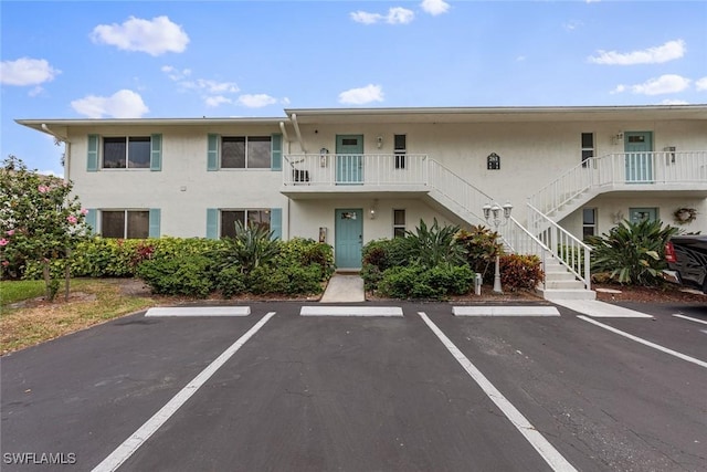 view of property featuring stairs and uncovered parking