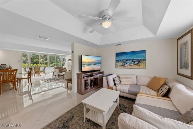 living area with light tile patterned floors, a ceiling fan, visible vents, and a raised ceiling