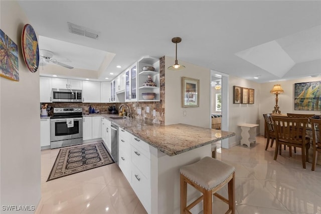 kitchen with light stone counters, open shelves, a sink, appliances with stainless steel finishes, and visible vents