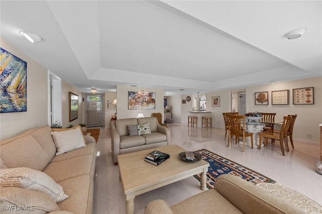 living room featuring baseboards, a raised ceiling, and light tile patterned flooring