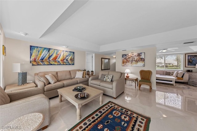 living area featuring ceiling fan, visible vents, and a raised ceiling