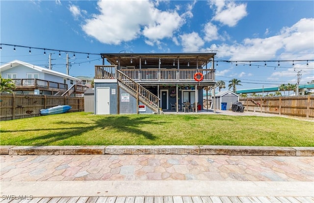 rear view of property featuring a deck, a fenced backyard, a storage unit, an outbuilding, and stairs