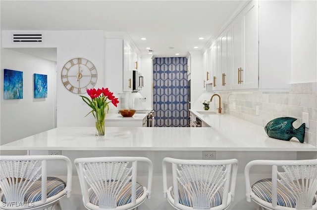 2100 Gulf Shore Blvd N Unit 108, Naples, FL 34102 - kitchen featuring stainless steel microwave, a sink, light countertops, white cabinetry, and a peninsula