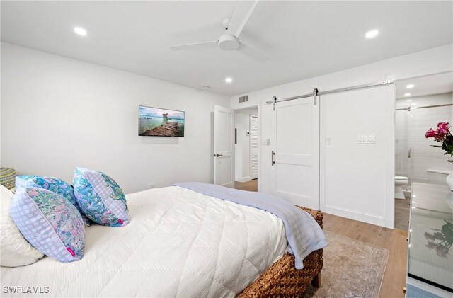 2100 Gulf Shore Blvd N Unit 108, Naples, FL 34102 - bedroom with a barn door, wood finished floors, recessed lighting, ceiling fan, and connected bathroom