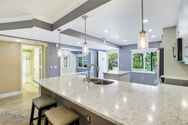 3051 Sandpiper Bay Cir Unit I102, Naples, FL 34112 - kitchen featuring a kitchen island, recessed lighting, stainless steel appliances, ornamental molding, and light stone countertops