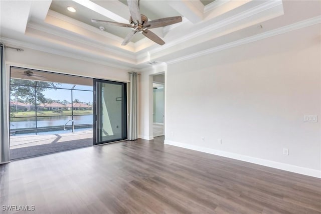 spare room featuring a raised ceiling, a water view, a ceiling fan, ornamental molding, and dark wood-style flooring