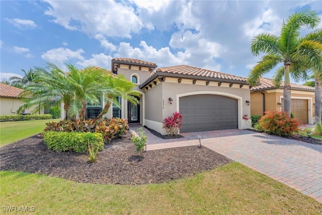 mediterranean / spanish home with stucco siding, a tiled roof, decorative driveway, and a garage