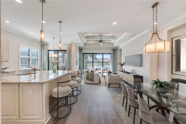 kitchen with ornamental molding, open floor plan, wood finished floors, and a sink