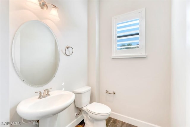 bathroom featuring wood finished floors, toilet, baseboards, and a sink
