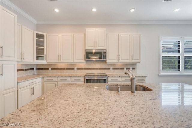 kitchen with tasteful backsplash, a sink, glass insert cabinets, white cabinets, and appliances with stainless steel finishes