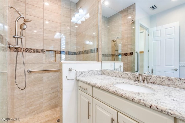 full bathroom featuring visible vents, vanity, and tiled shower